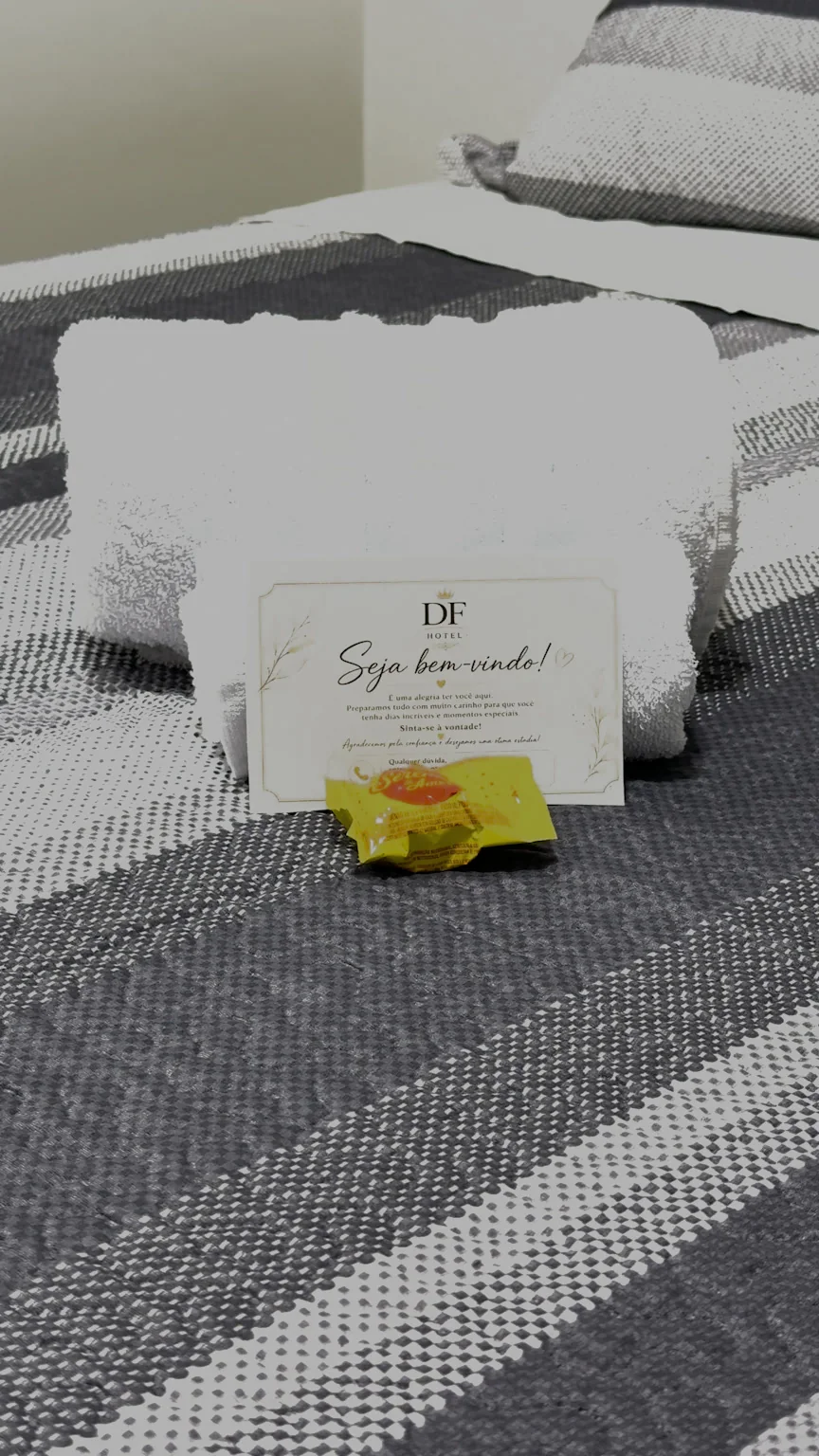 Toalhas dobradas e cartão de boas-vindas sobre a cama