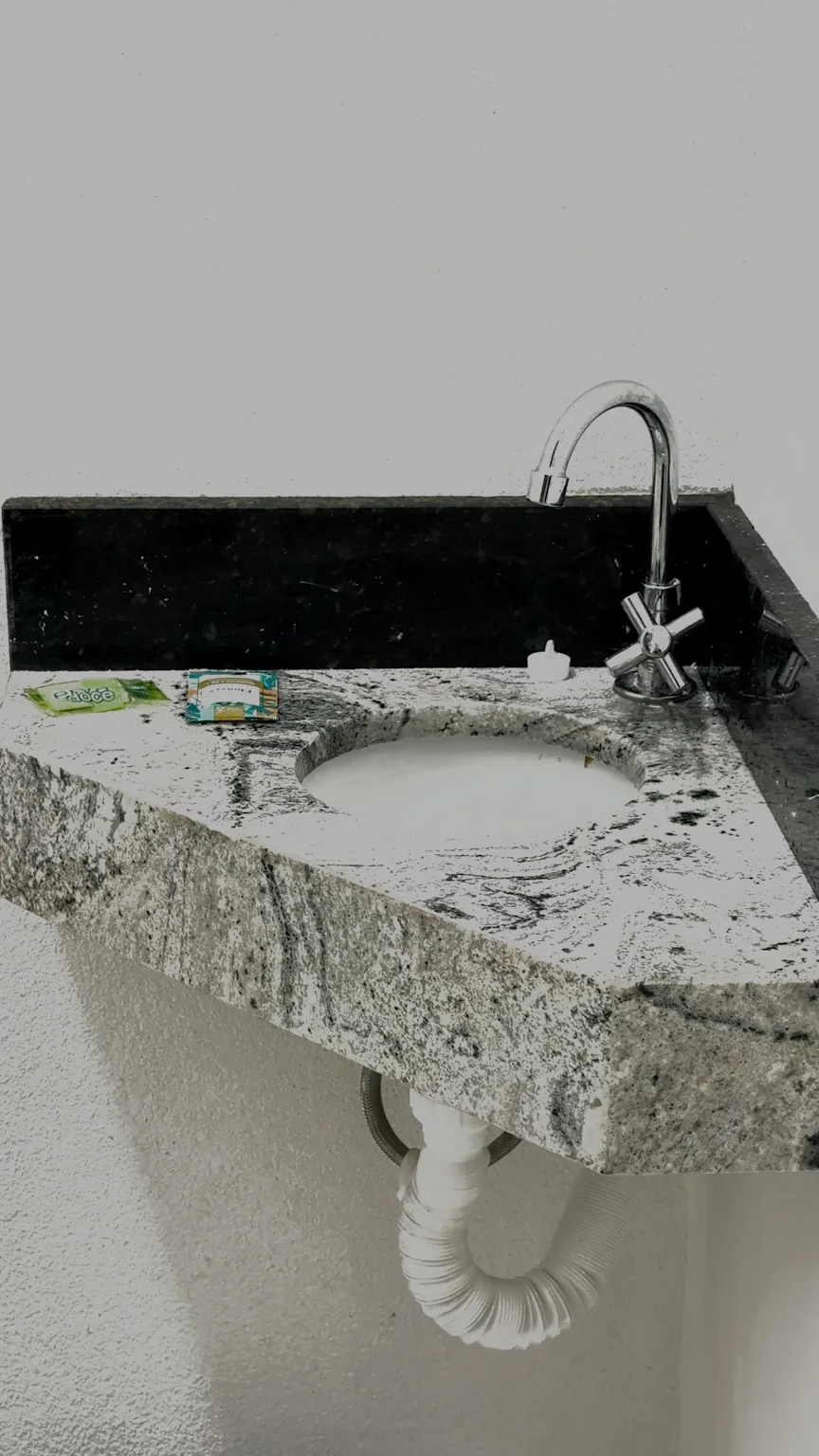 Bancada de granito com pia, torneira e produtos de higiene