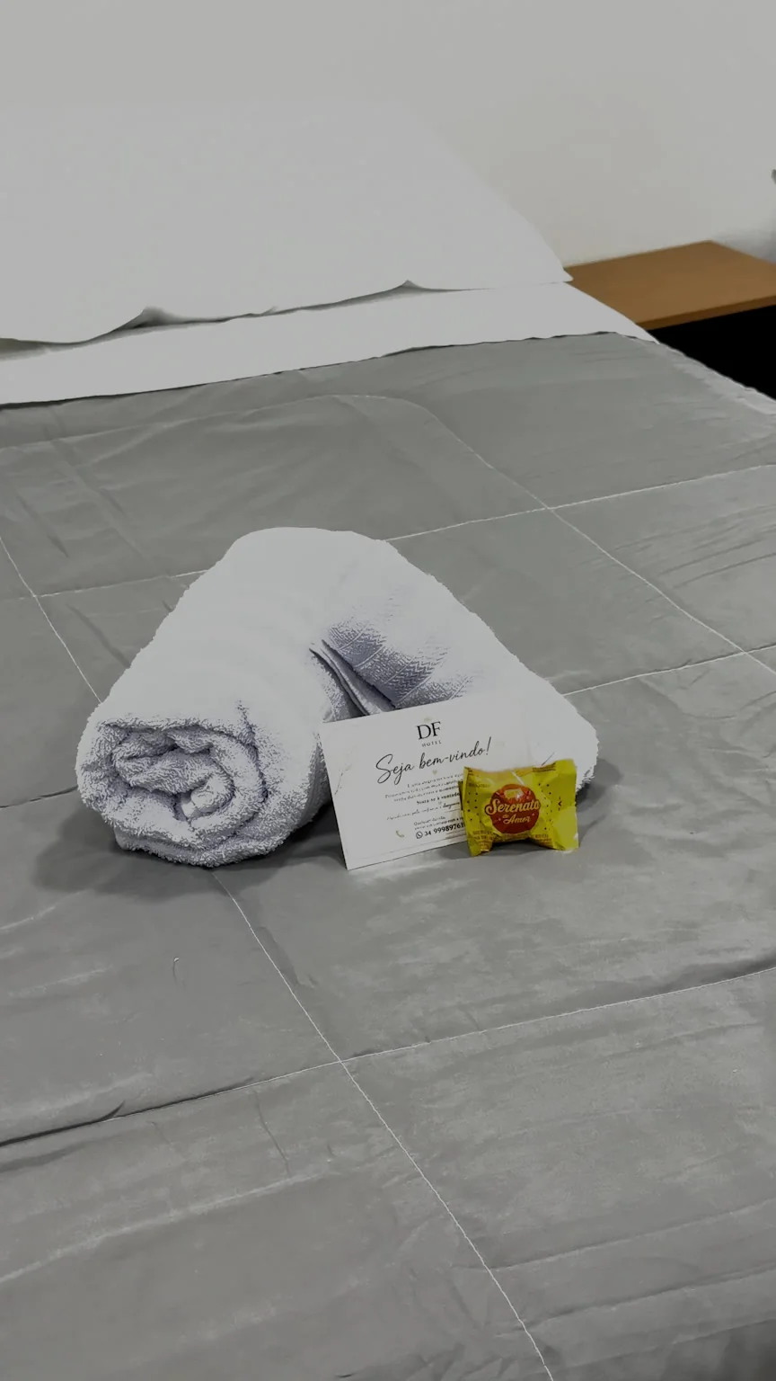 Toalhas dobradas sobre a colcha cinza de uma cama