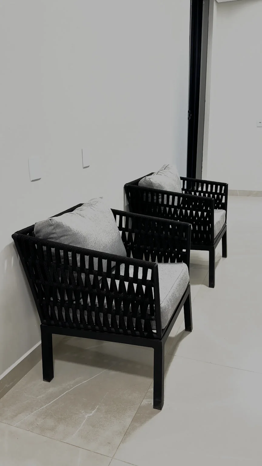 Poltronas com estrutura escura e almofadas claras em um corredor do hotel